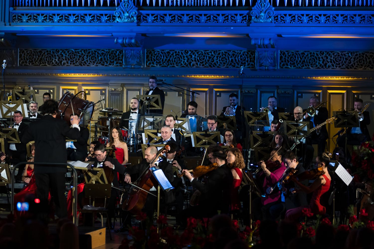 Orchestra Simfonică București în timpul concertului, cu dirijorul în prim-plan, la Ateneul Român